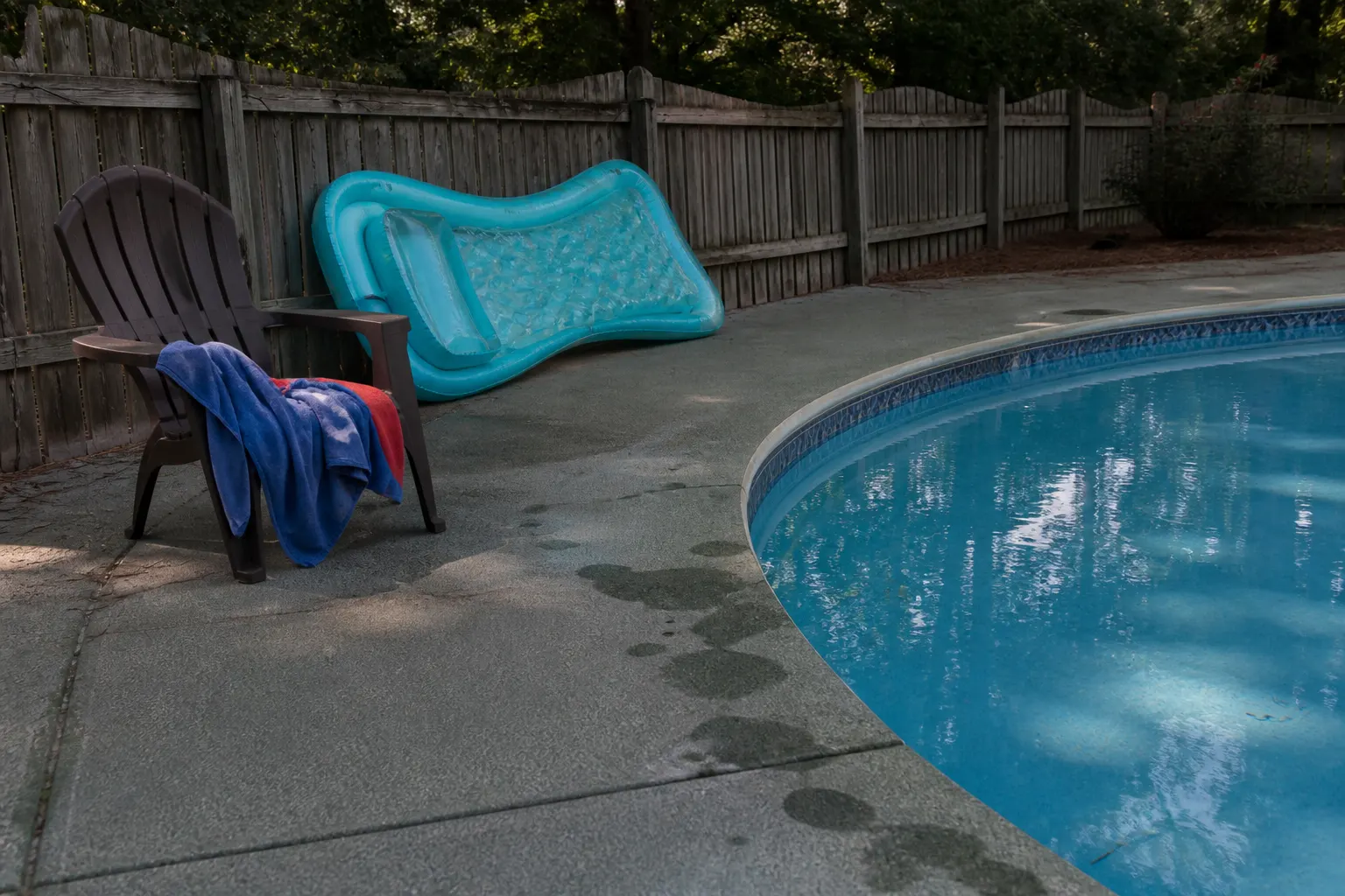 Textured pool deck coating with damp patches near the water