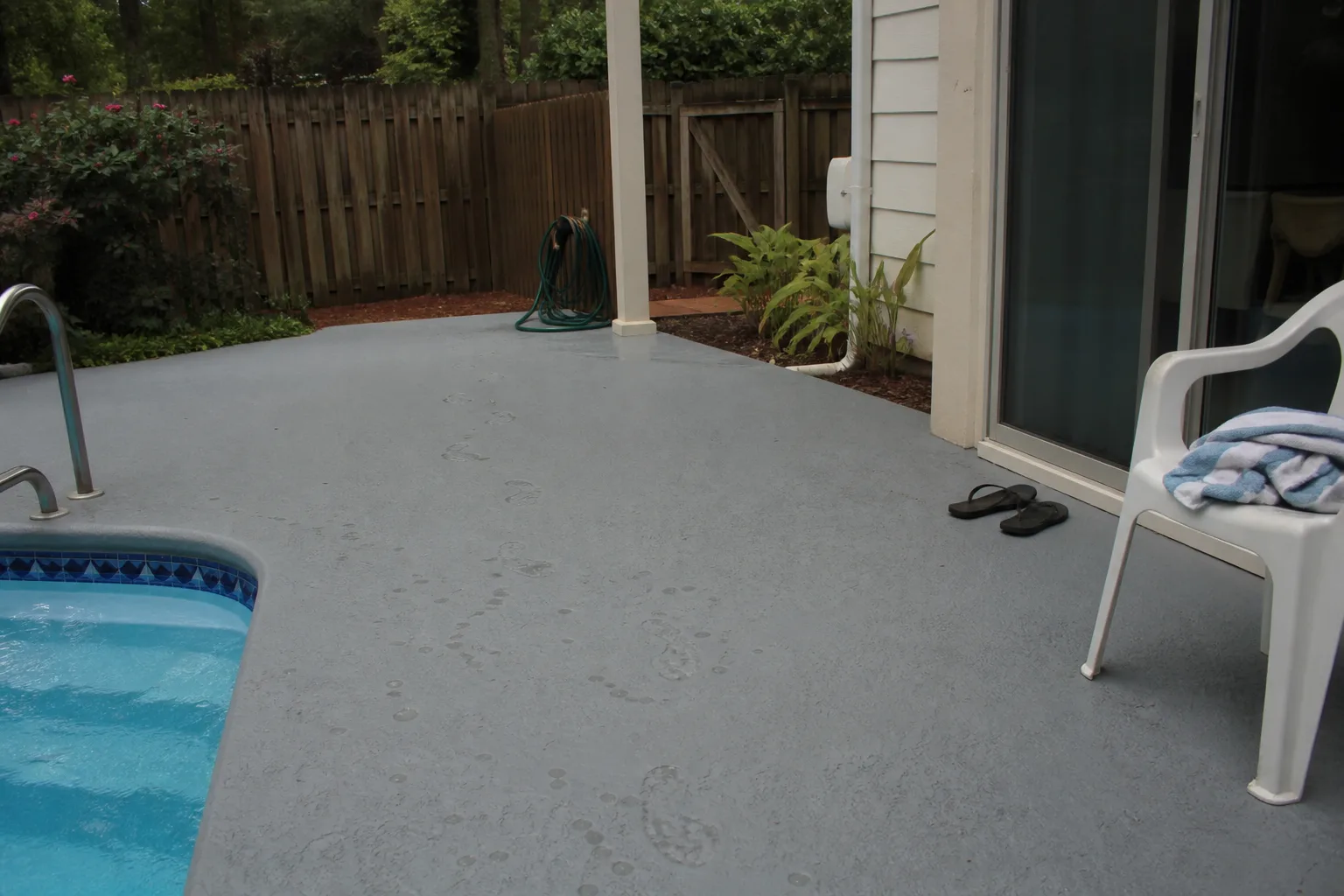 Textured matte pool deck coating with wet footprints showing traction